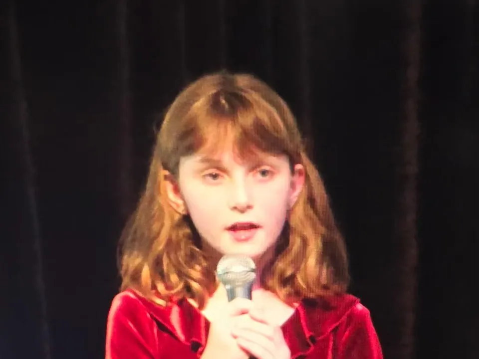 Dakota Allison as a young voice student singing at a Mojo's recital